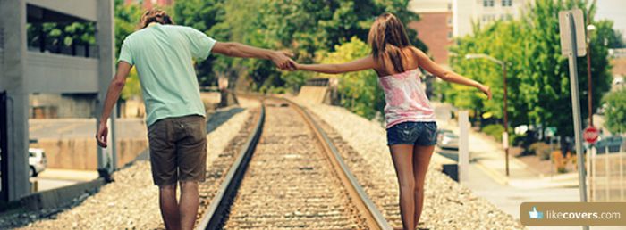 Couple holding hands walking on the railroad